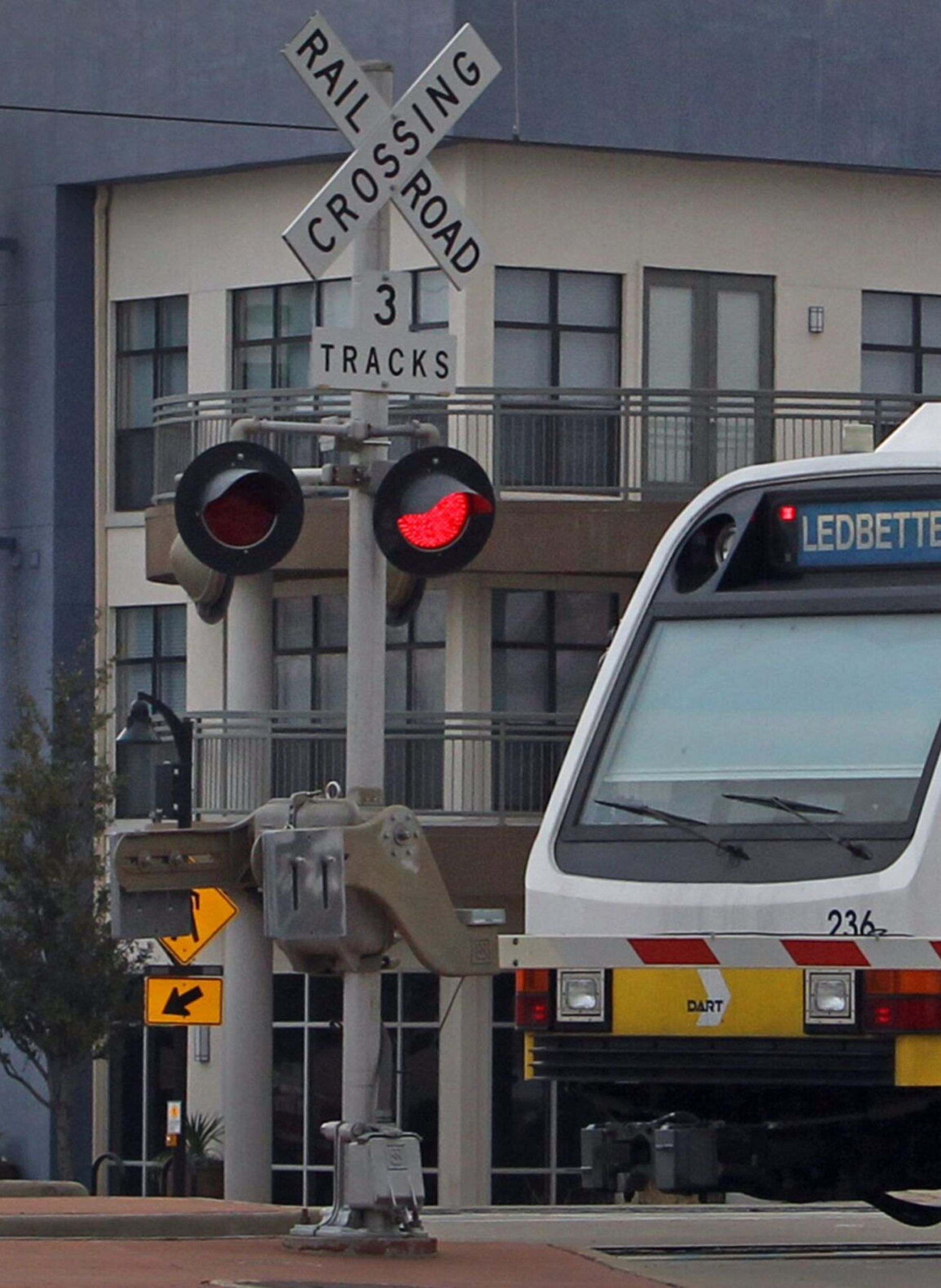 Valley Creek Light rail train at a crossing with signals and barriers in an urban area.