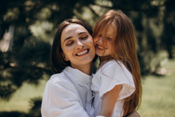 Valley Creek A smiling woman and child embrace outdoors in a green, sunny setting.