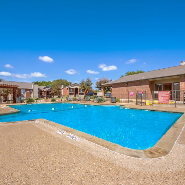 Valley Creek Outdoor swimming pool with clear blue water, surrounded by a concrete deck, lounge chairs, and red brick buildings.