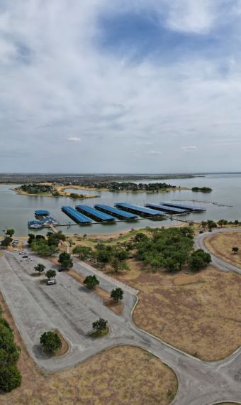 Valley Creek Aerial view of a lakeside area with a marina, roads, and lush greenery under a cloudy sky.