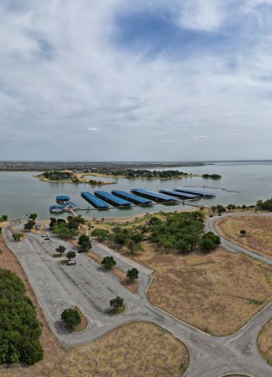 Valley Creek Aerial view of a lakeside area with a marina, roads, and lush greenery under a cloudy sky.