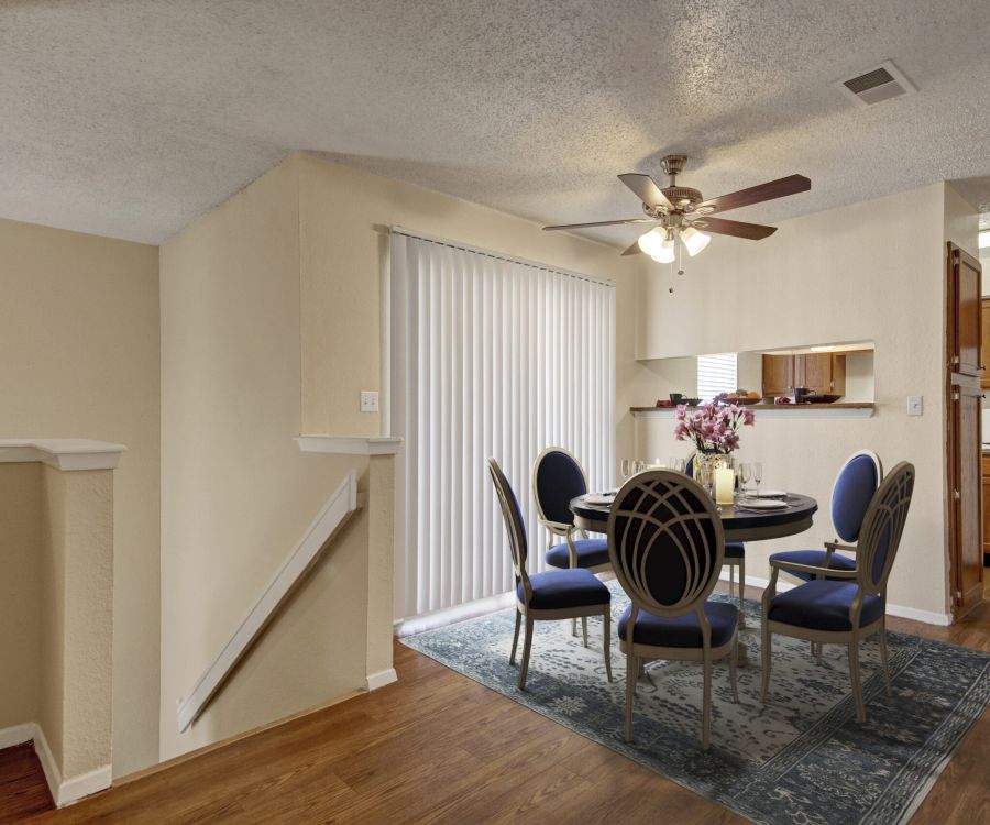 Valley Creek Dining area with a round table, five chairs, ceiling fan, and a vase of flowers next to a kitchen with wooden cabinets.