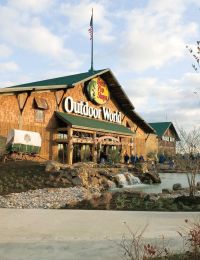 Valley Creek Bass Pro Shops Outdoor World store with a landscaped entrance and trees under a partly cloudy sky.