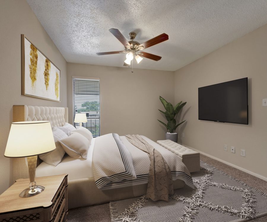 Valley Creek A cozy bedroom with a bed, lamp, large TV, ceiling fan, and potted plant, featuring neutral tones and natural light.