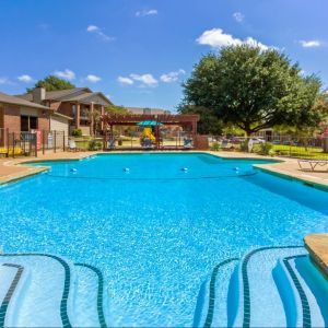 Valley Creek Outdoor swimming pool surrounded by lounge chairs and buildings under a clear blue sky. Outdoor pool with lounge chairs, surrounded by houses and trees under a clear blue sky.